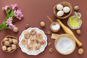 Delicious fresh homemade buns and dough ingredients: eggs, vegetable oil, sugar and rye flour on brown kitchen table. Recipe. Easter and holiday baking. Flat lay, copy space, closeup, top view
