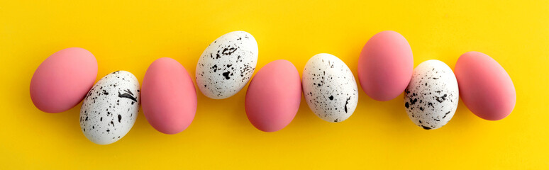Flat lay top view of white and pink eggs with minimal designs on yellow background