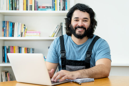 Laughing handyman with beard working at computer