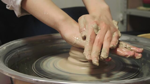 Woman working with wet clay on pottery wheel, closeup. Ceramic art