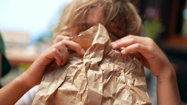 One child hiding behind a paper bag kid covering face