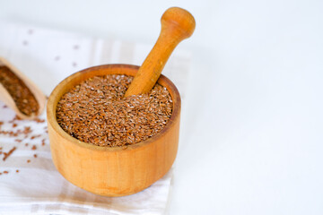 Flax seeds in a round plate with wooden spoon on a linen napkin in a kitchen. Ingredient for flaxseed porridge and jelly. Minimalistic simple natural light template. Superfood. Organic eco healthcare.