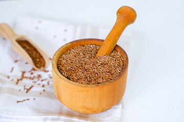 Flax seeds in a round plate with wooden spoon on a linen napkin in a kitchen. Ingredient for flaxseed porridge and jelly. Minimalistic simple natural light template. Superfood. Organic eco healthcare.