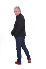 Fototapeta premium rear view of a man dressed in a blazer and jeans turning around looking at the camera with his hands in his pockets