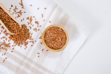 Flax seeds in a round plate with wooden spoon on a linen napkin in a kitchen. Ingredient for flaxseed porridge and jelly. Minimalistic simple natural light template. Superfood. Organic eco healthcare.