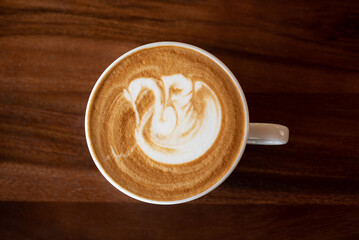 Cup of hot latte art coffee on wooden table