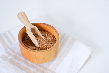 Flax seeds in a round plate with wooden spoon on a linen napkin in a kitchen. Ingredient for flaxseed porridge and jelly. Minimalistic simple natural light template. Superfood. Organic eco healthcare.