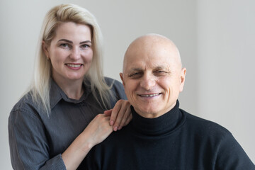 Grown up loving attentive caring granddaughter hugging elderly 75s grandfather. Young adult daughter embracing aged father looking at distance in cozy living room. Concept of family ties love and care