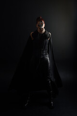 Full length portrait of pretty redhead female model wearing black futuristic scifi leather cloak...