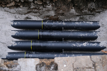 lot of new black pipes for protecting electrical wires in trench on street, concept of repairing urban communications, conducting electrical networks, laying optical fiber for communication