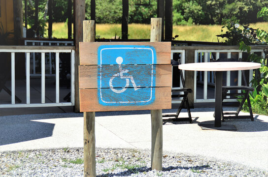 Uma placa feita em madeira indicando vaga de estacionamento de carros para deficientes