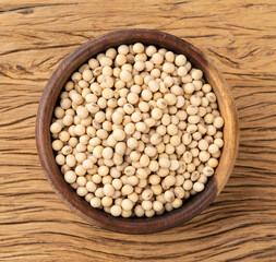 Uncooked soy beans in a bowl over wooden table