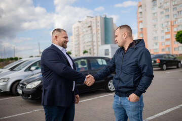 Photo of auto seller discussing with client about car model..People shaking hands with each other..Successful car sale-purchase transaction.