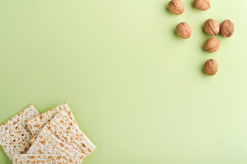 Passover celebration concept. Matzah, red kosher wine and walnut. Traditional ritual Jewish bread on light green background. Passover food. Pesach Jewish holiday.