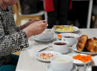 An elderly woman sits at a table in the dining room of the sanatorium and eats. Healthy delicious...