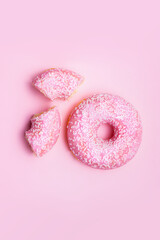 background pink glazed donut on pink background, whole and halved.