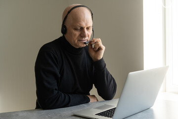 Portrait of grey-haired senior handsome smiling man working from home. Communication online with colleagues and video conference. Online meeting, video call, remote working