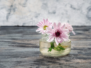 A small bouquet of pink chrysanthemums in a glass jar