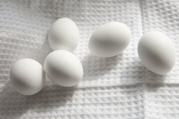 Five white chicken eggs on a cotton white waffle towel. Easter, home cooking concept.