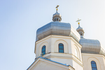 White church on sunny day. Ortodox cathedral on clear blue sky background. Religious architecture. Faith and pray concept. Ukrainian culture. Church with cross on the roof.