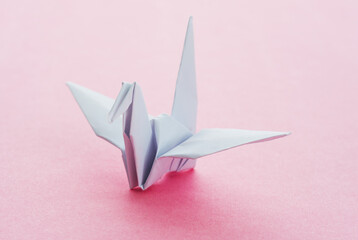 White origami paper crane on pink background