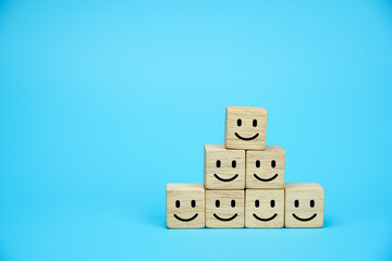 Smiling face icons on wooden cubes. Business service rating, customer satisfaction or teamwork concept. on blue background.                        