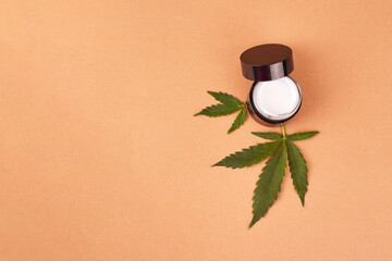 Fototapeta na wymiar Moisturizing cream in black jar with CBD oil cannabis leaf. Cannabis essential oil. Herbal cosmetic. Space for text.