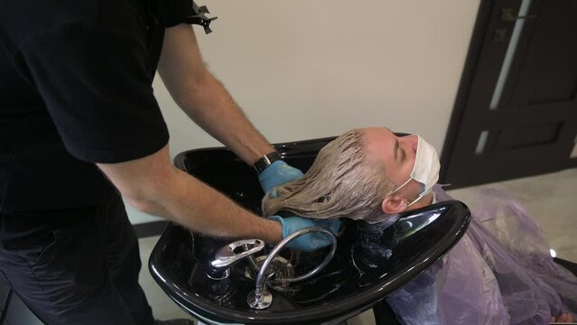 Hairdresser washing woman's hair in hairdresser salon. Hair care and professional treatment concepts
