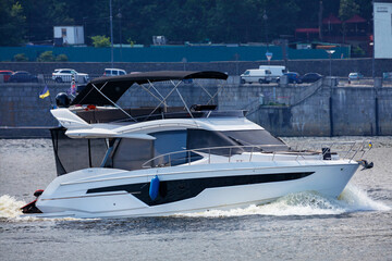 Fototapeta premium A speedboat cuts through the river waters against the backdrop of the city's stone embankment.