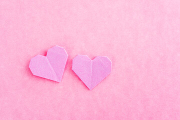 Pink origami hearts on pink background