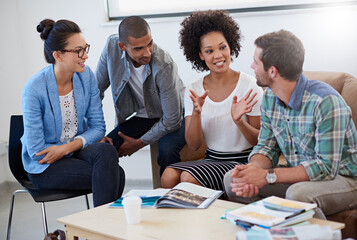 Were making progress. Shot of a group of designers having a meeting around a coffee table.