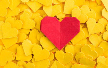 Red origami heart on yellow origami hearts