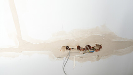 View of electrical wires hanging from a wall during apartment remodeling