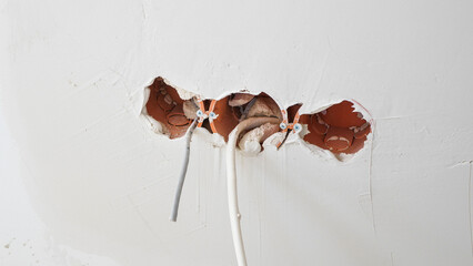 View of electrical wires hanging from a wall during apartment remodeling