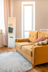 Bright interior of the room with a yellow sofa and mirror