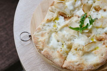Roman round pizza five or four cheeses on a round wooden kitchen pizza board. Delicious fresh...