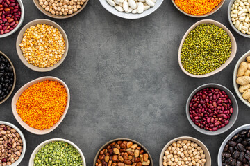 Frame of various types of legumes in bowls, green and yellow peas, chickpeas and peanuts, colored beans and lentils, mung beans and beans, top view, copy space