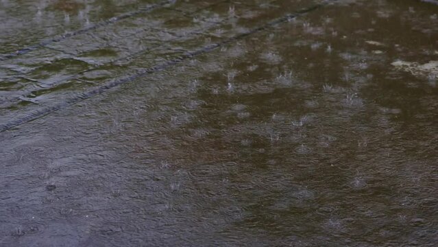 Heavy rain on stamped concrete in slow motion