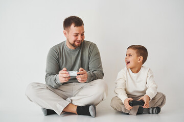 Emotional family playing console games on a white background. Father and son play gamepad games together.