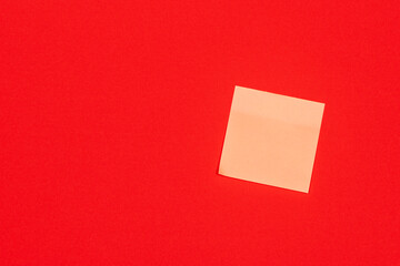 Yellow paper adhesive note stuck to a red background.