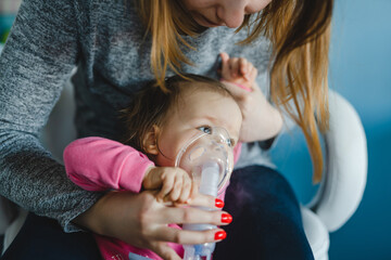 one baby and mother using nebulizer at home Woman hold her small girl child using vapor steam inhaler mask inhalation at home medical procedure medicament treatment asthma pneumonia bronchitis - obrazy, fototapety, plakaty