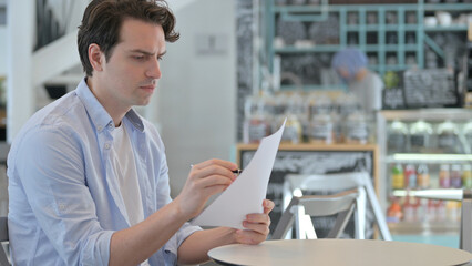 Creative Man Reading Documents in Cafe 