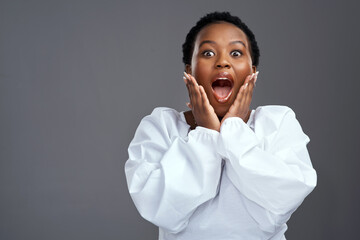 You dont want to miss out. Shot of a young woman looking surprised while posing against a grey background.