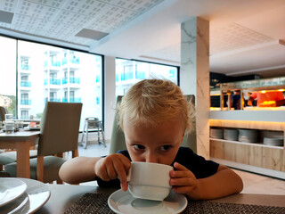 child drinking cocoa in a public place