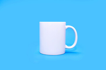 White mug on a blue background in the center. A white cup with any drink on an empty uniform blue background. Cafe or snack concept. White mug with the possibility of advertising or logo