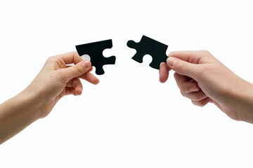 Two hands connect a puzzle on a white background close-up. The concept of finding a solution to a problem or friendship. Puzzles develop logic and attention in children