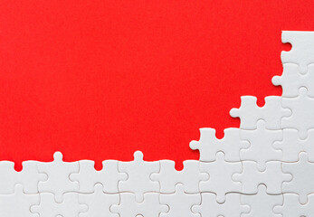 Unfinished white puzzle pieces on red background