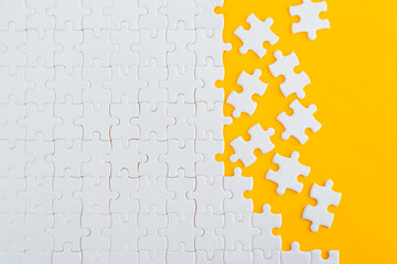 Unfinished white puzzle pieces on yellow background