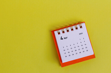 Desktop calendar for April 2022 for planning on a yellow background.