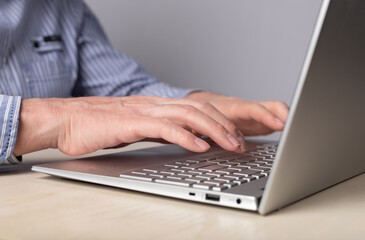 Man hands closeup typing on laptop keyboard. Using computer for distant work, online education, social communication. High quality photo